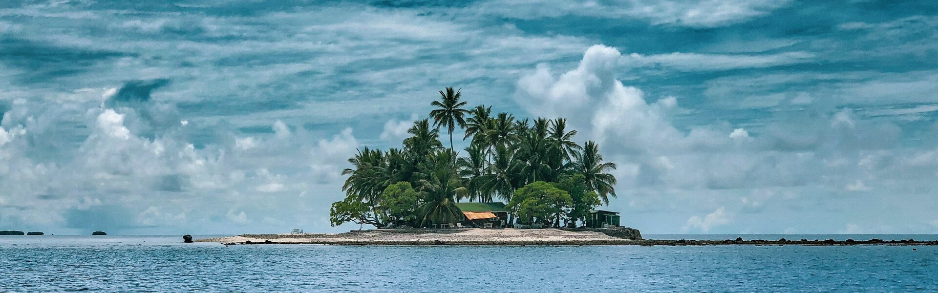 Insel mit Palmen im Meer, Wolken am Himmel